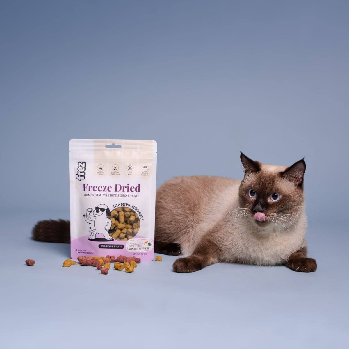 A cat licking its lips with the Frez Joints Health Freeze Dried Beef with Spinach & Turmeric Treats beside it.