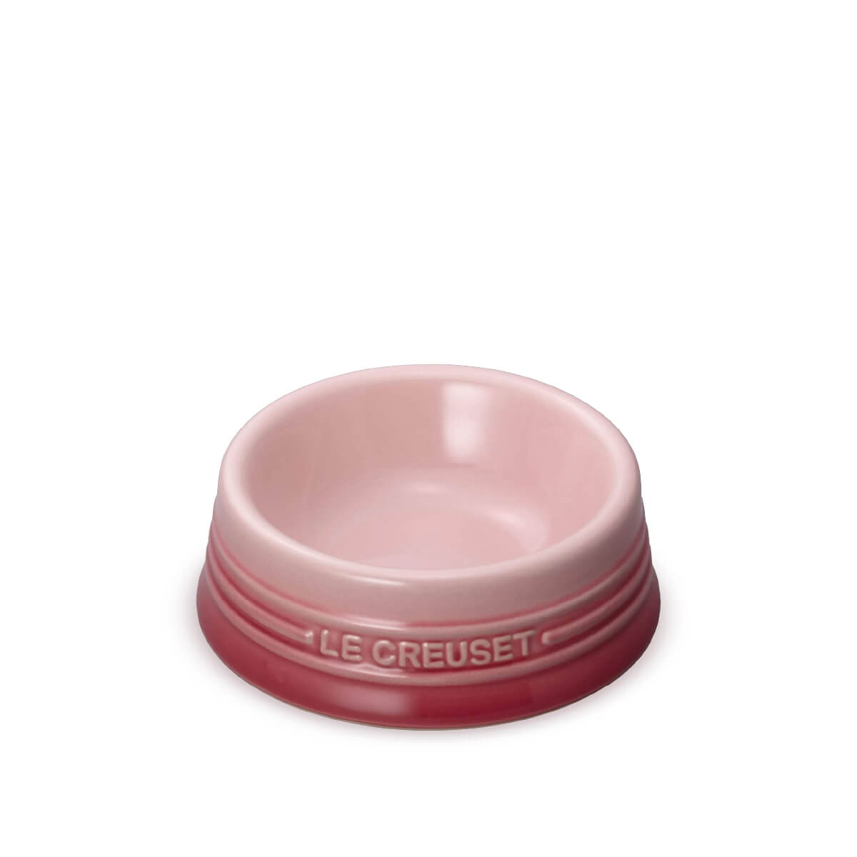 A Le Creuset Pale Rose ceramic pet bowl in a two-tone pink colorway, featuring a light pink interior and a darker rose pink exterior with the brand name embossed on the rim, set against a plain white background.