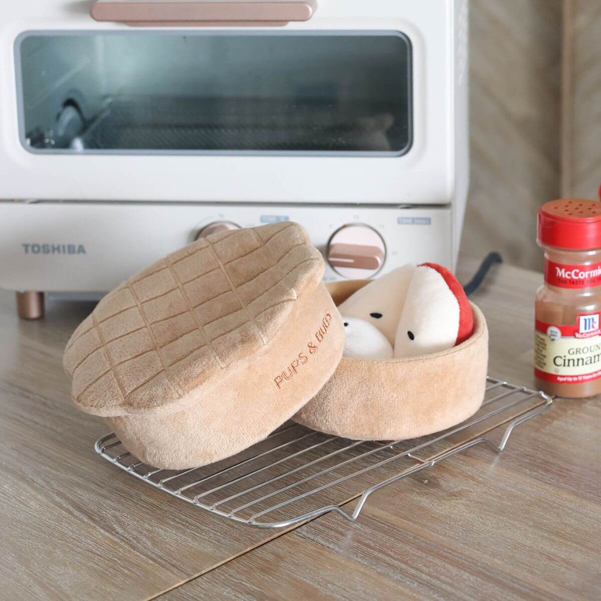 The Pups and Bubs Apple Pie Nosework Toy on a rack in front of a toaster oven.