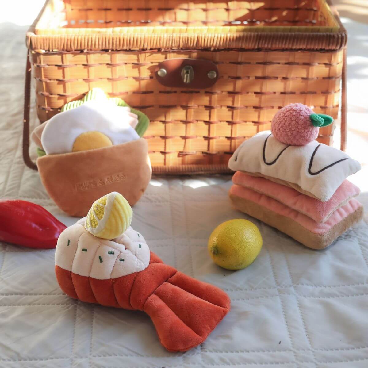 Pups and Bubs Grilled Lobster Nosework Toy near a picnic basket.