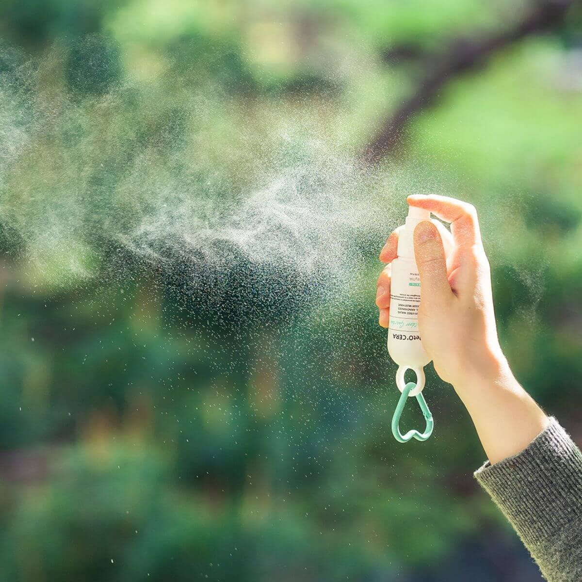 The PetO'CERA Outdoor Guardian Mist used outdoors against greenery.