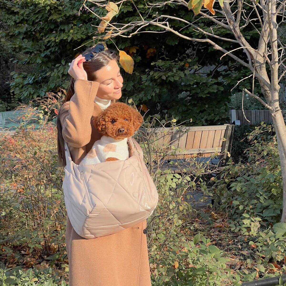 Pups & Bubs Cloud Crossbody Carrier in Latte against lush greenery.