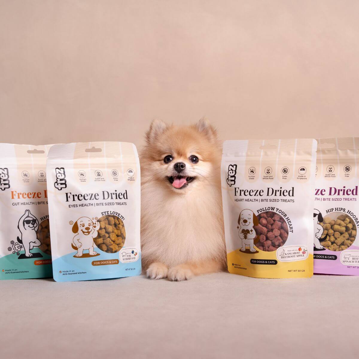 A pomeranian in the middle with 2 packets of Frez treats of each side.