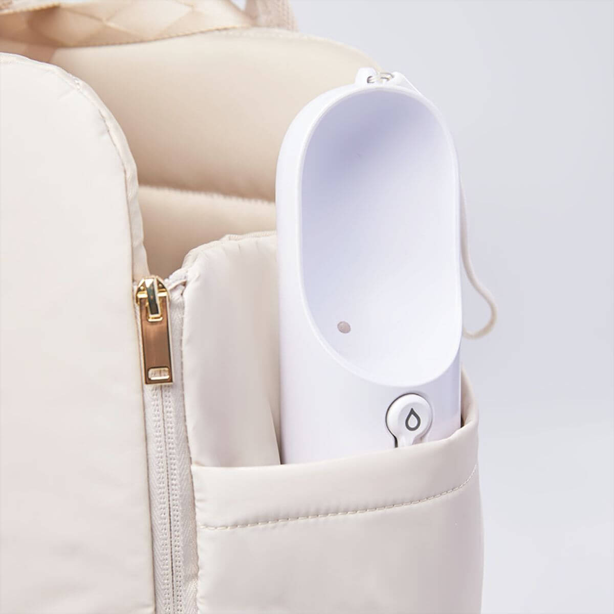 Pups and Bubs Everywhere Convertible Tote Bag Carrier in sand with a bottle in the side pockets.