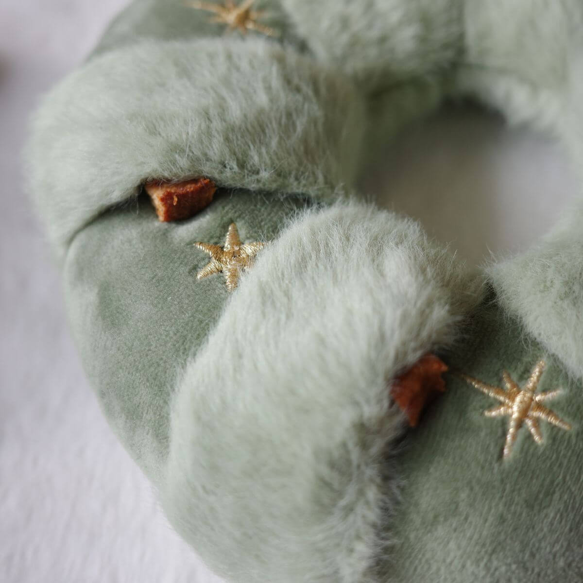 Pups & Bubs Festive Wreath Nosework Toy against a white background with treats in the hidden pockets.
