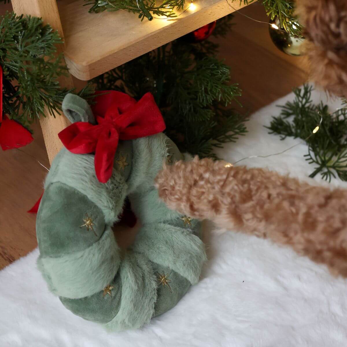 A poodle reaching out a paw for the Pups & Bubs Festive Wreath Nosework Toy. 