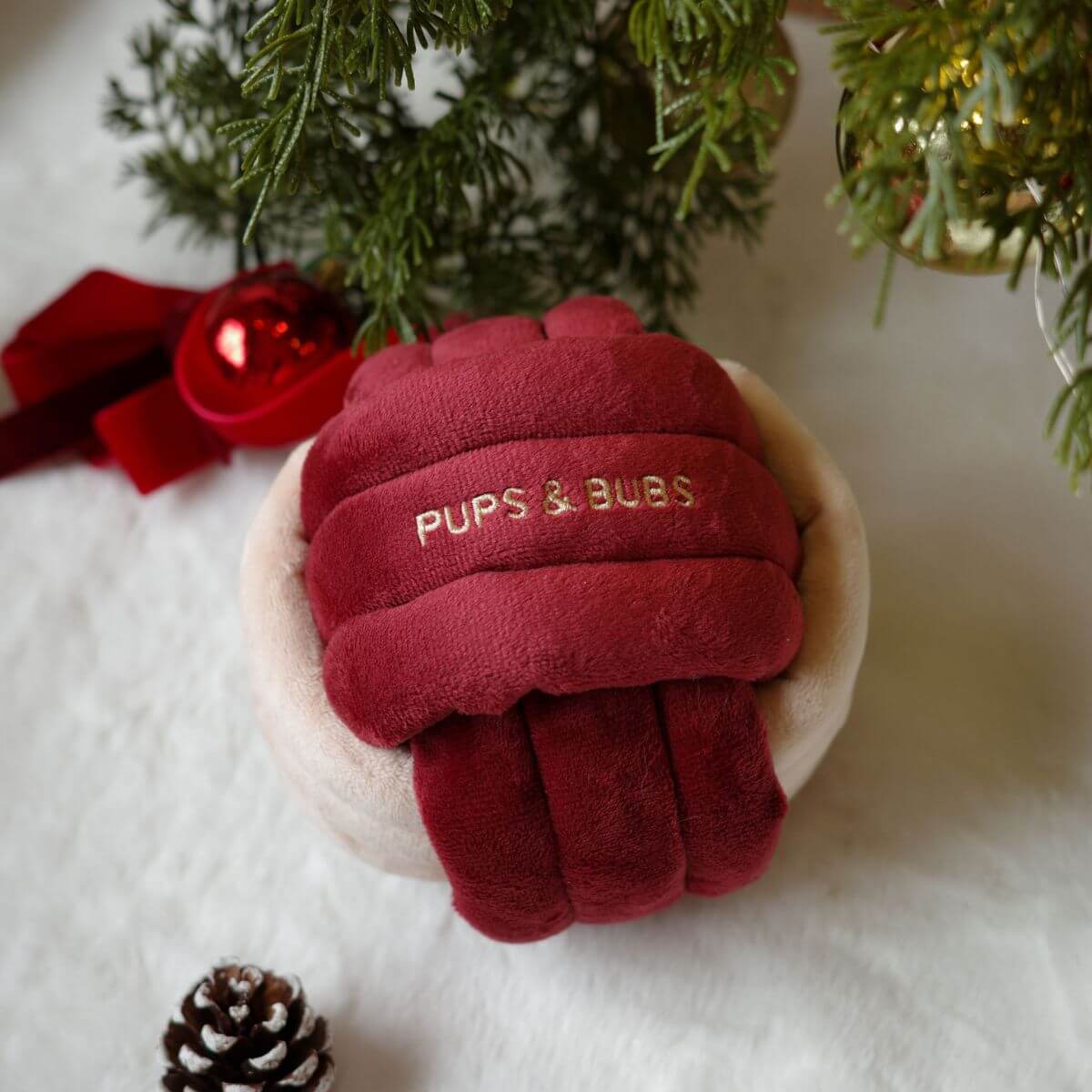 Pups and Bubs Jingle Know Nosework Toy against a white background with a Christmas tree, baubles and pine cones.