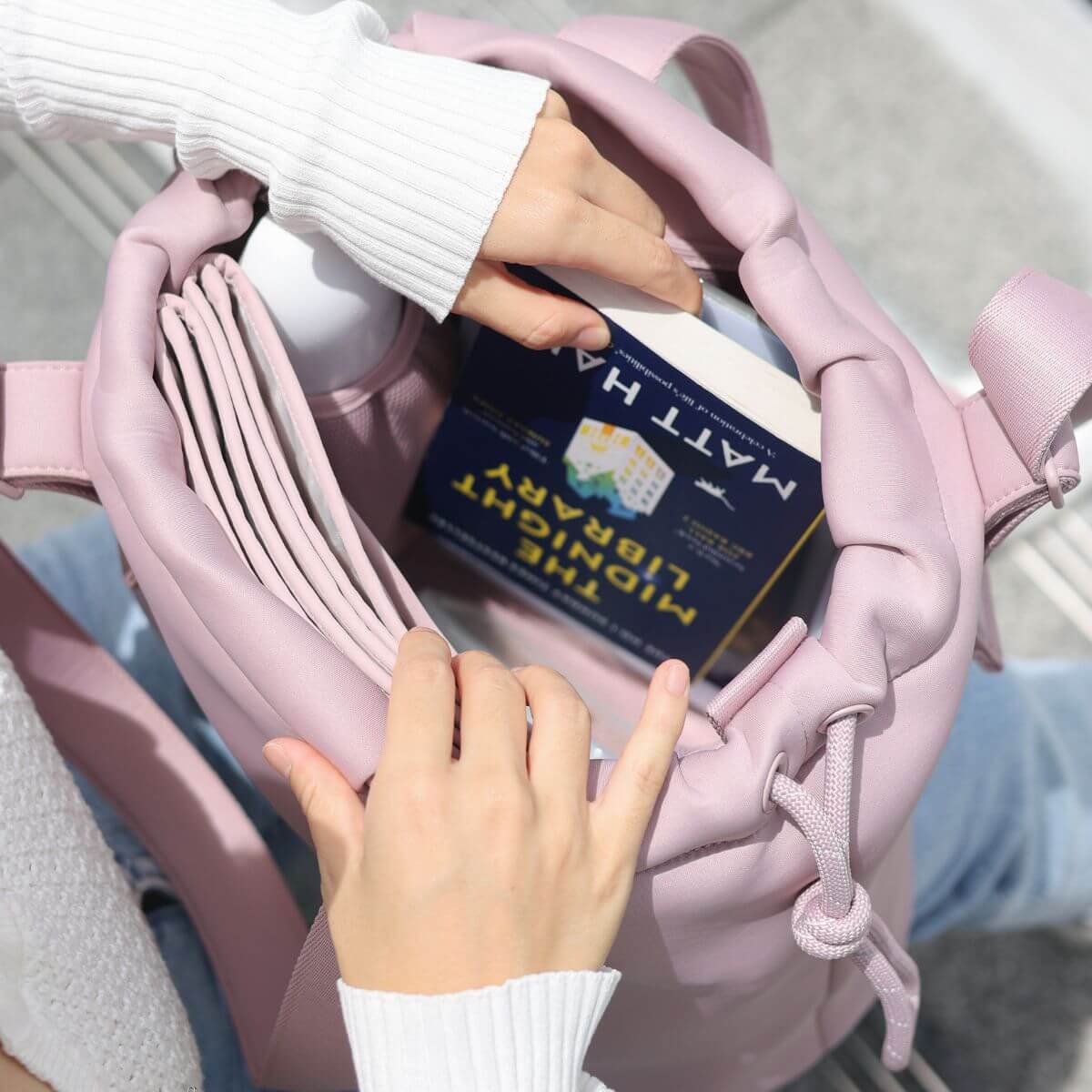 A woman taking out a book from the Pups and Bubs All Day Chill Bag in Rose. 