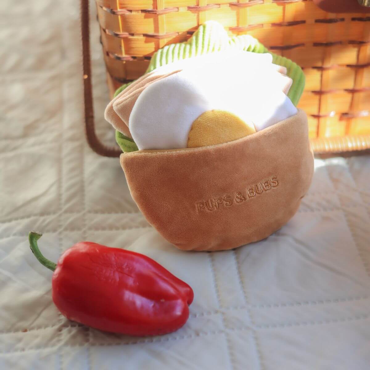 The Pups and Bubs Pita Pocket leaning on a picnic basket.