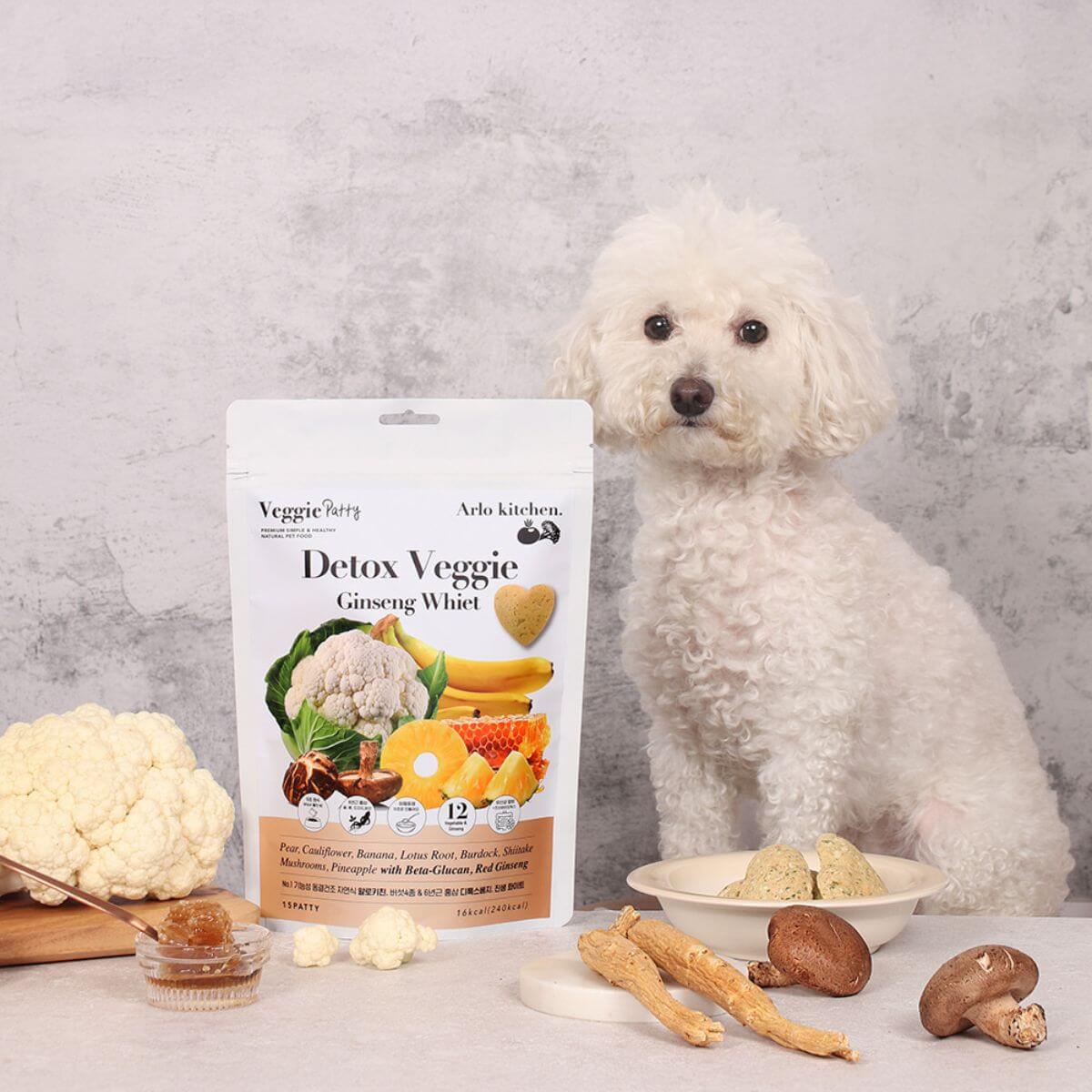 A poodle mix posing with the Arlo Kitchen Detox White Veggie Patties. 