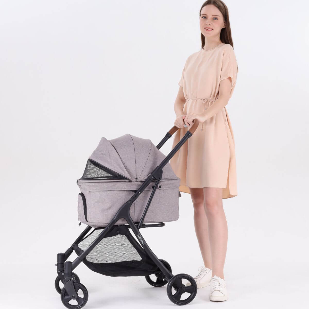 A woman pushing the Bernd Pets Autofold Lina in Manatee Grey against a white background.