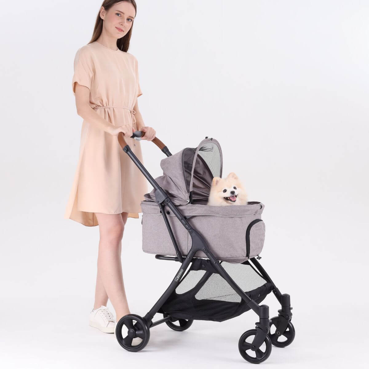 A woman pushing the Bernd Pets Autofold Lina in Manatee Grey against a white background.