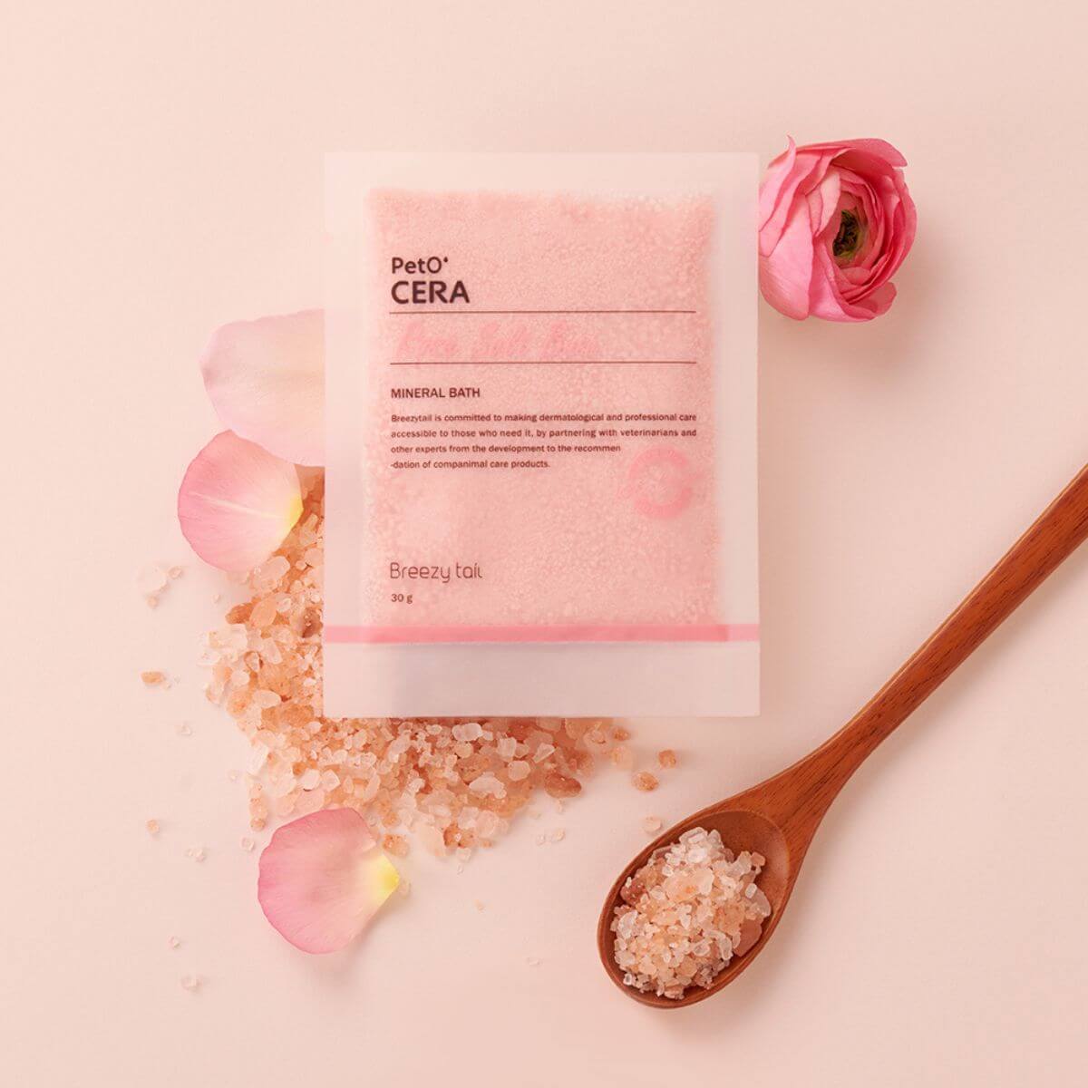 PetO'CERA Spa Rose Salt Bath against a pink background with petals and salt on a wooden spoon.
