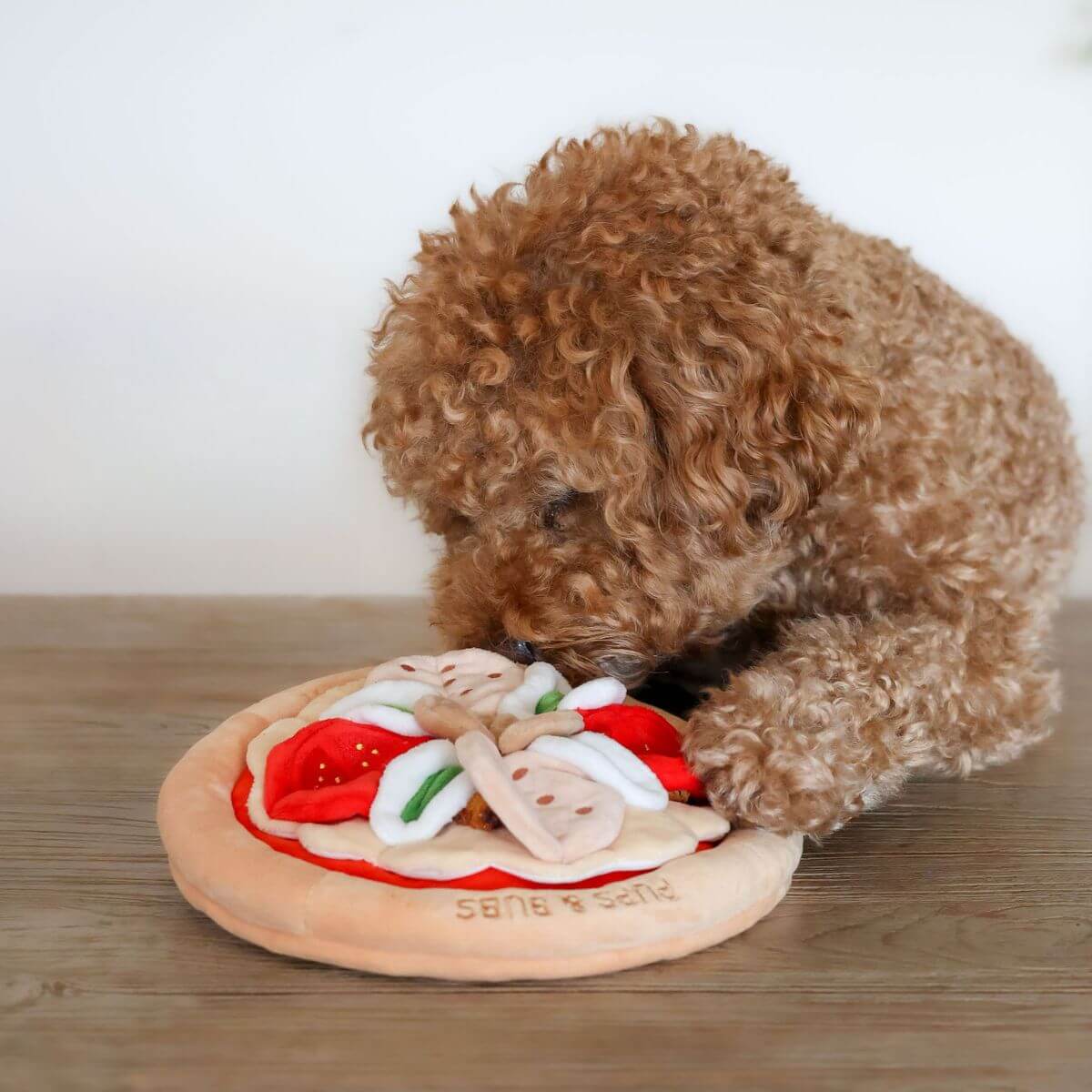 Pups & Bubs Pepperoni Pizza Snuffle Mat and a brown poodle sniffing it.