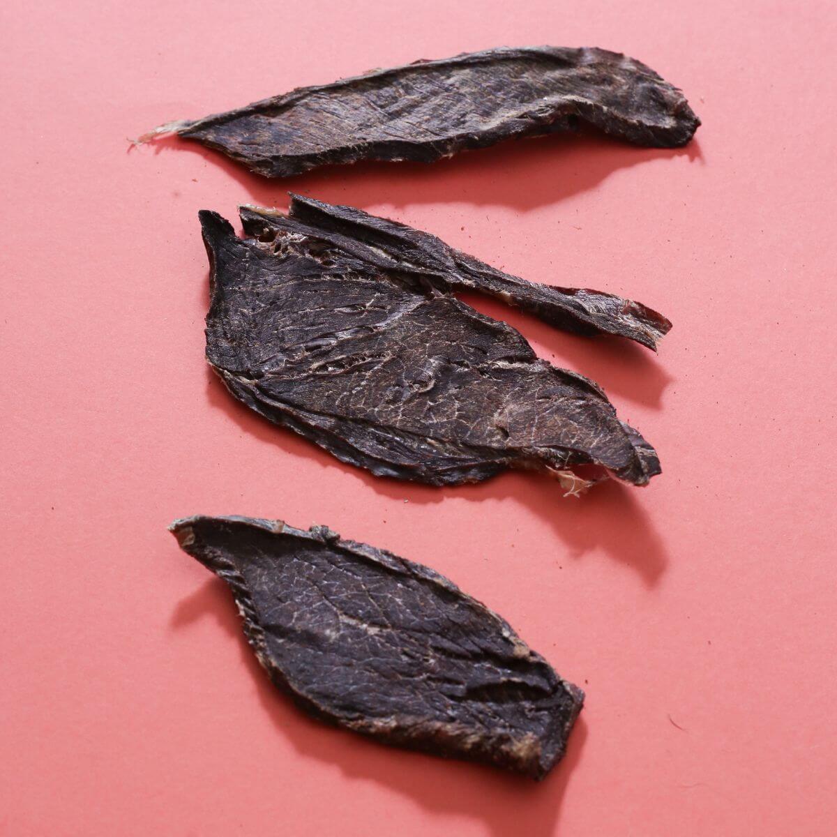 taki pets naaf venison lean meat against a pink background.