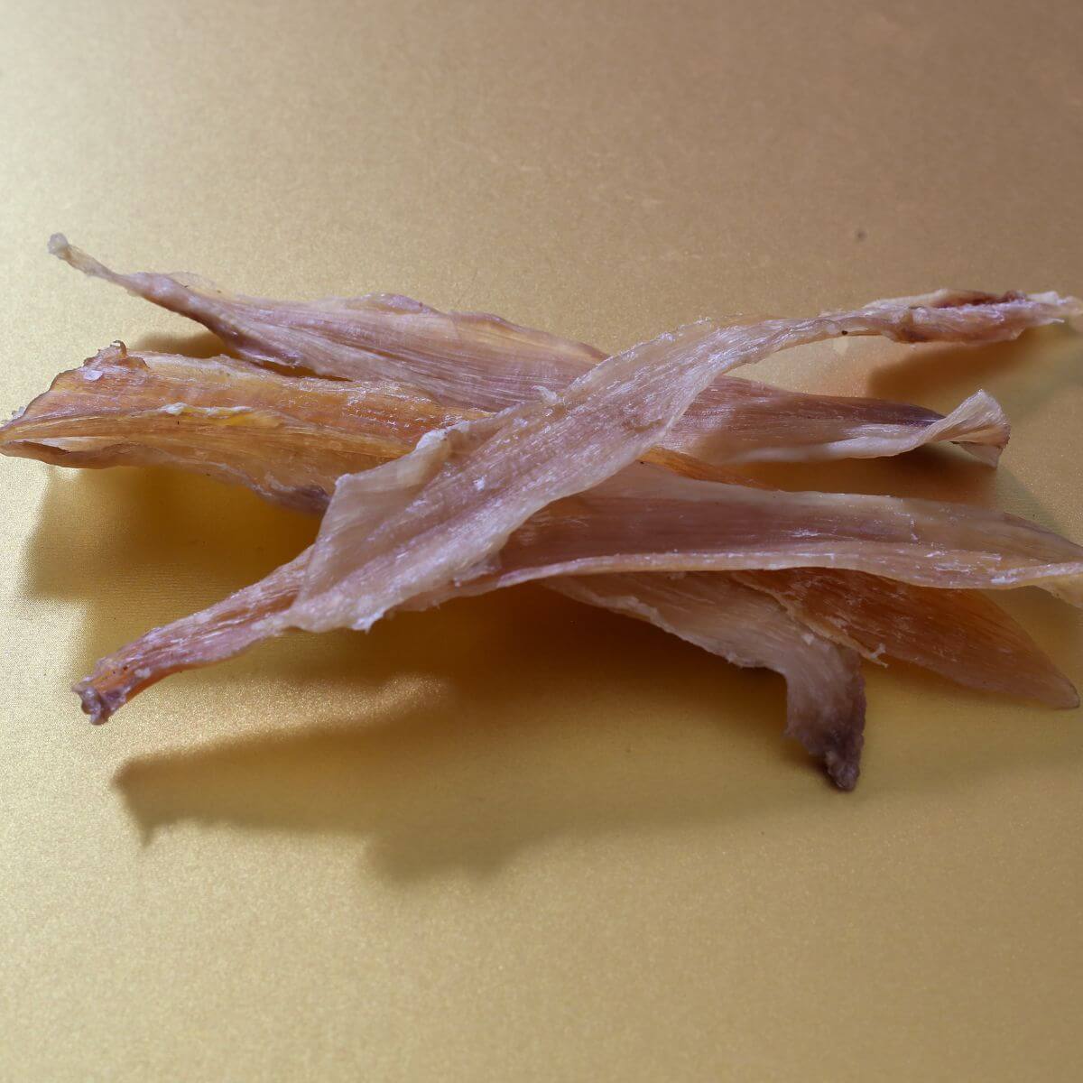 taki pets naad wagyu thigh tendon short against a gold background.