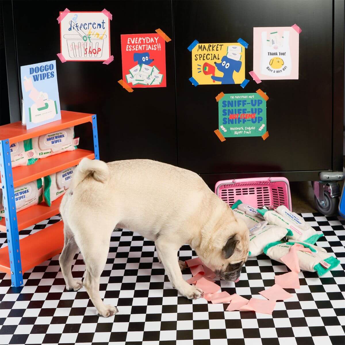 A pug sniffing the the furryfolks doggo wipe nosework toy against a supermarket background.