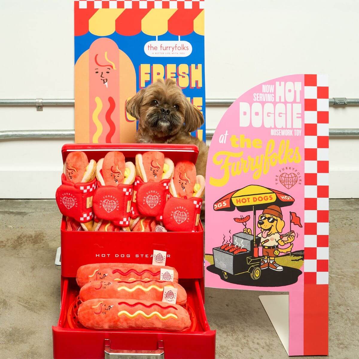 A dog posing behind a hot dog stand of the the furryfolks hot doggie nosework toy. 