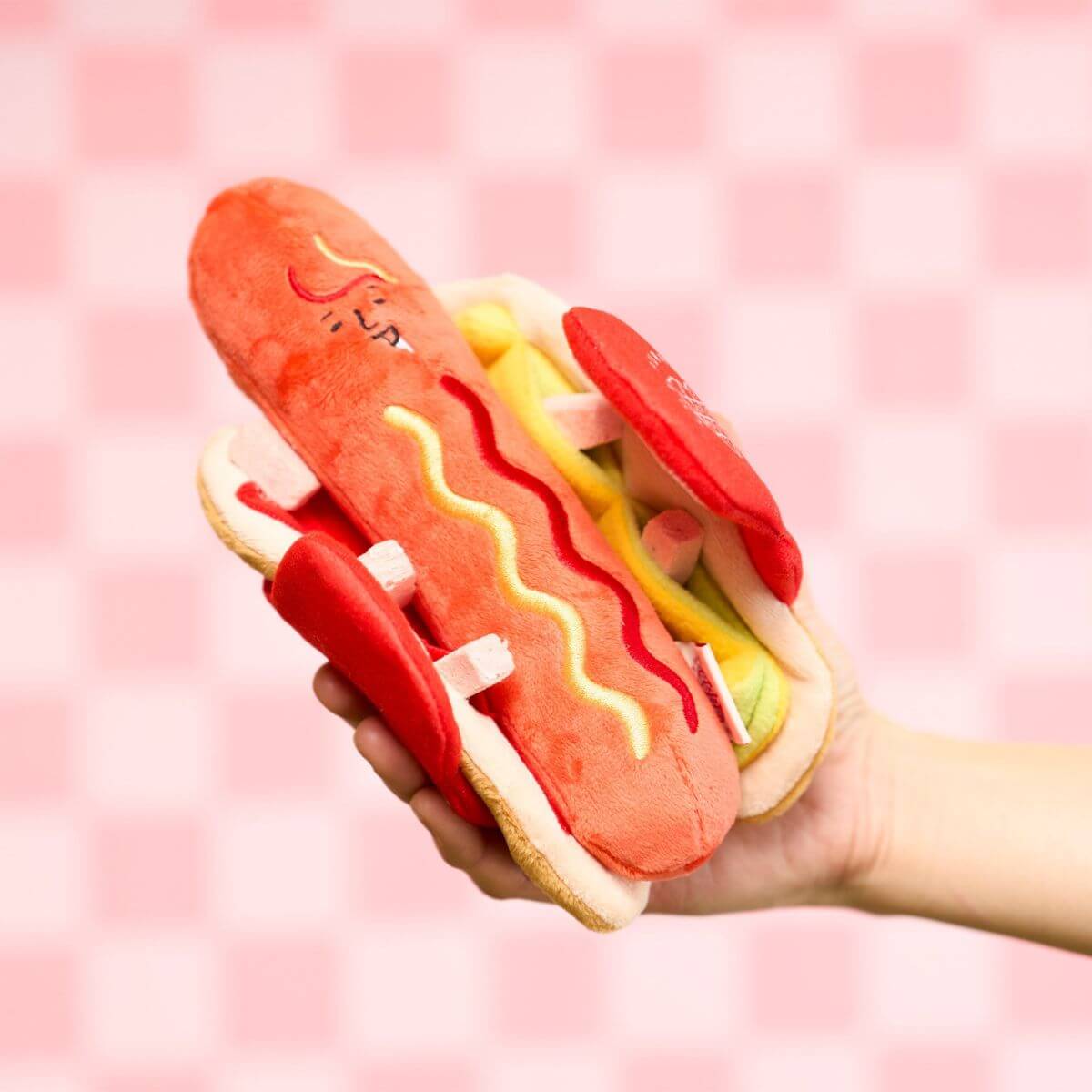 the furryfolks hot doggie nosework toy against a pink and white checkered background.